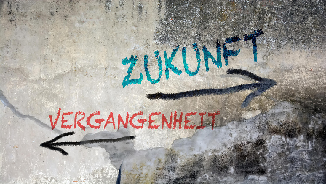 Ein Graffito an einer Hauswand: Zukunft und Vergangenheit zeigen in entgegengesetzte Richtungen