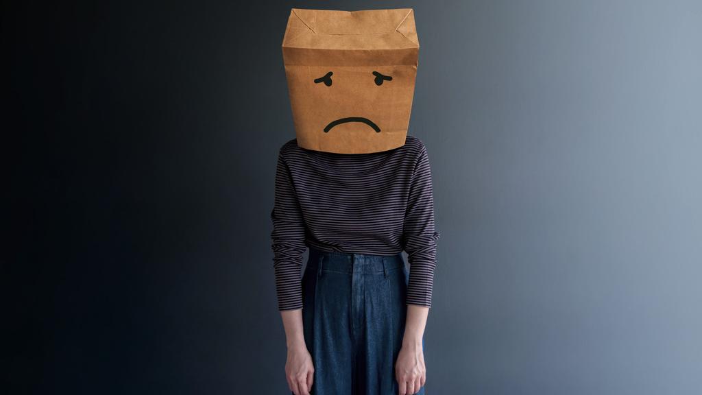 Person mit Papiertüte über dem Kopf mit traurigem Gesicht