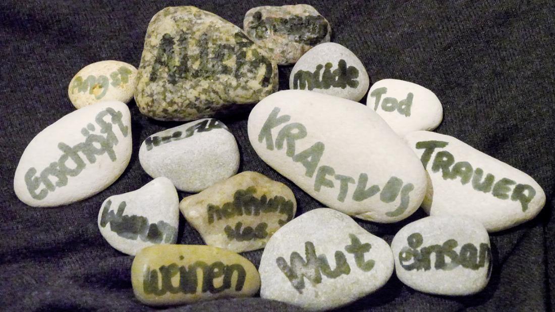 Die Kinder schreiben auf Steine Worte der Trauer.