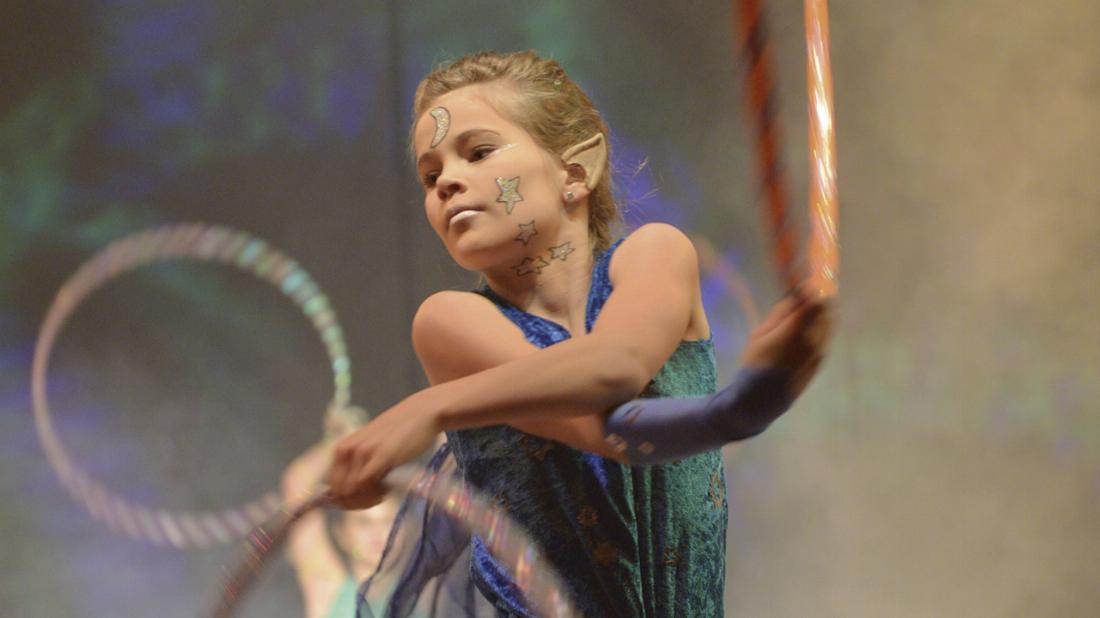Mädchen im Kostüm zeigt Kür mit Hula-Hoop-Reifen